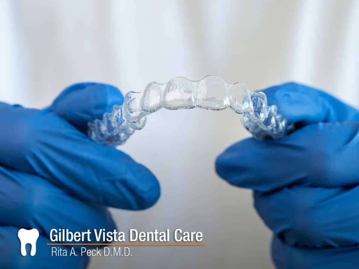 Hands holding removable retainers for dental alignment