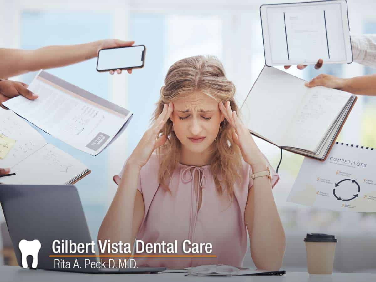 Stressed woman overwhelmed at work, showing the stress impact oral health can have when left unmanaged.
