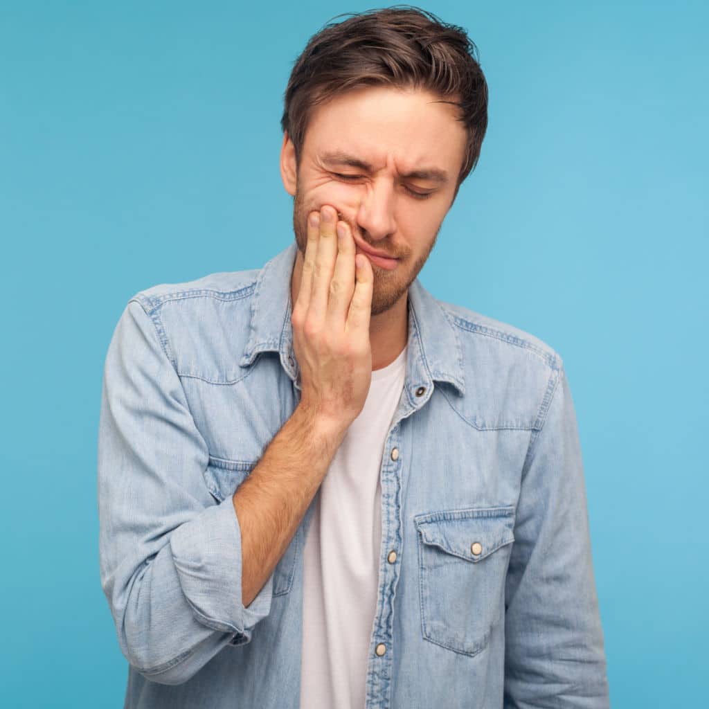 Man holding jaw in pain from an infected tooth needing root canal therapy